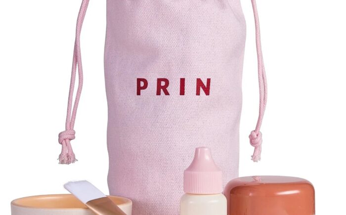 Pink skincare set with brush, cream, and dropper.